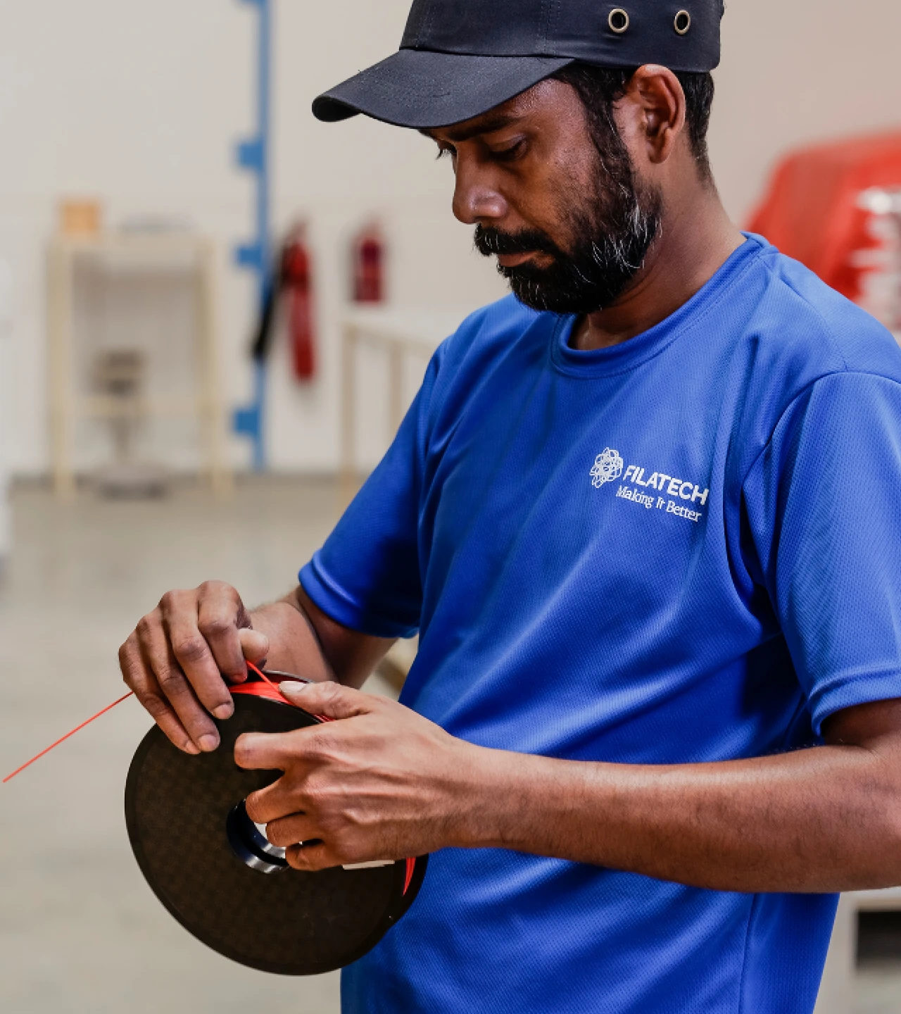 Filatech technician handling 3D filament spool in manufacturing facility